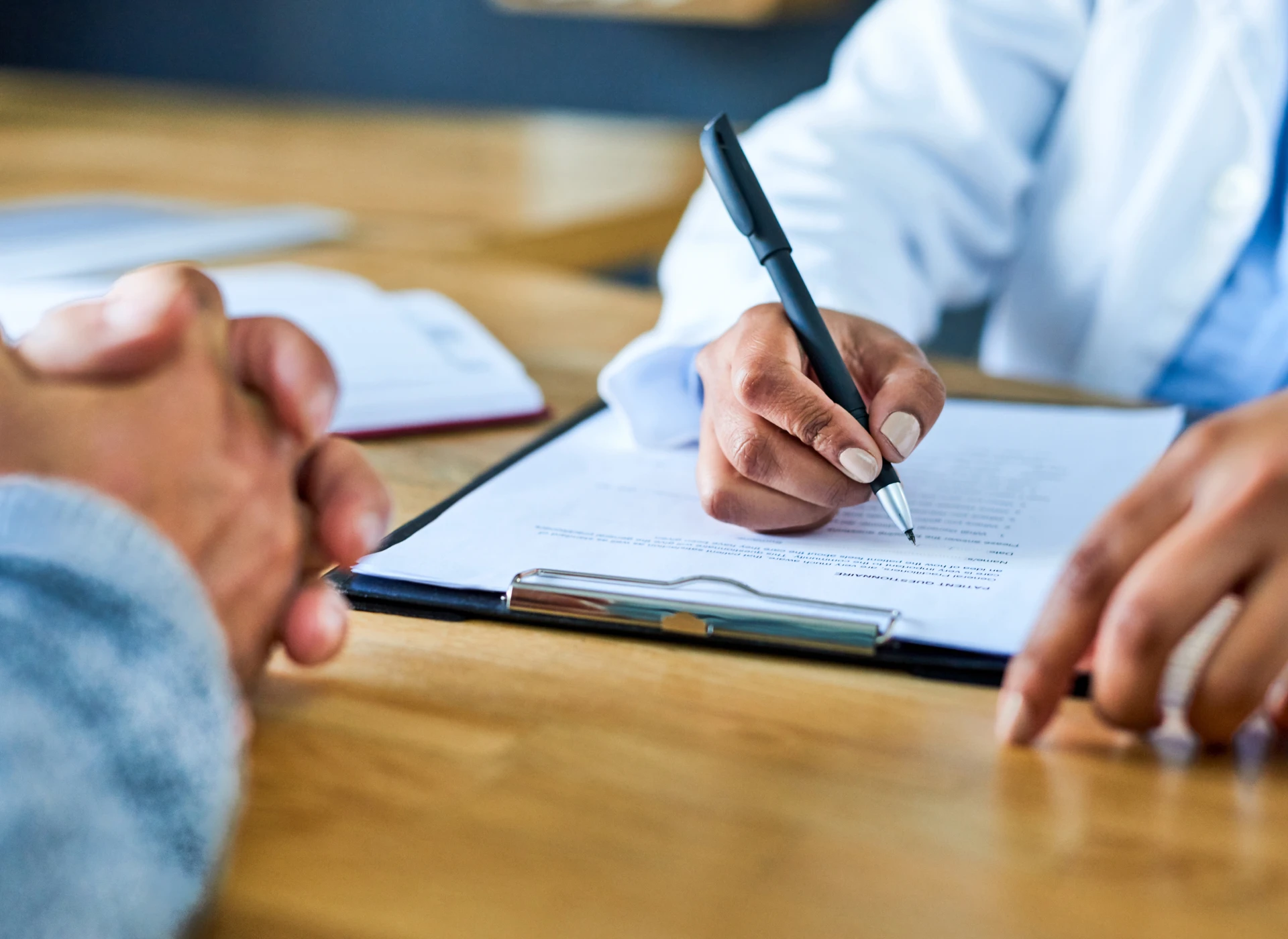 Hands signing a document on clipboard